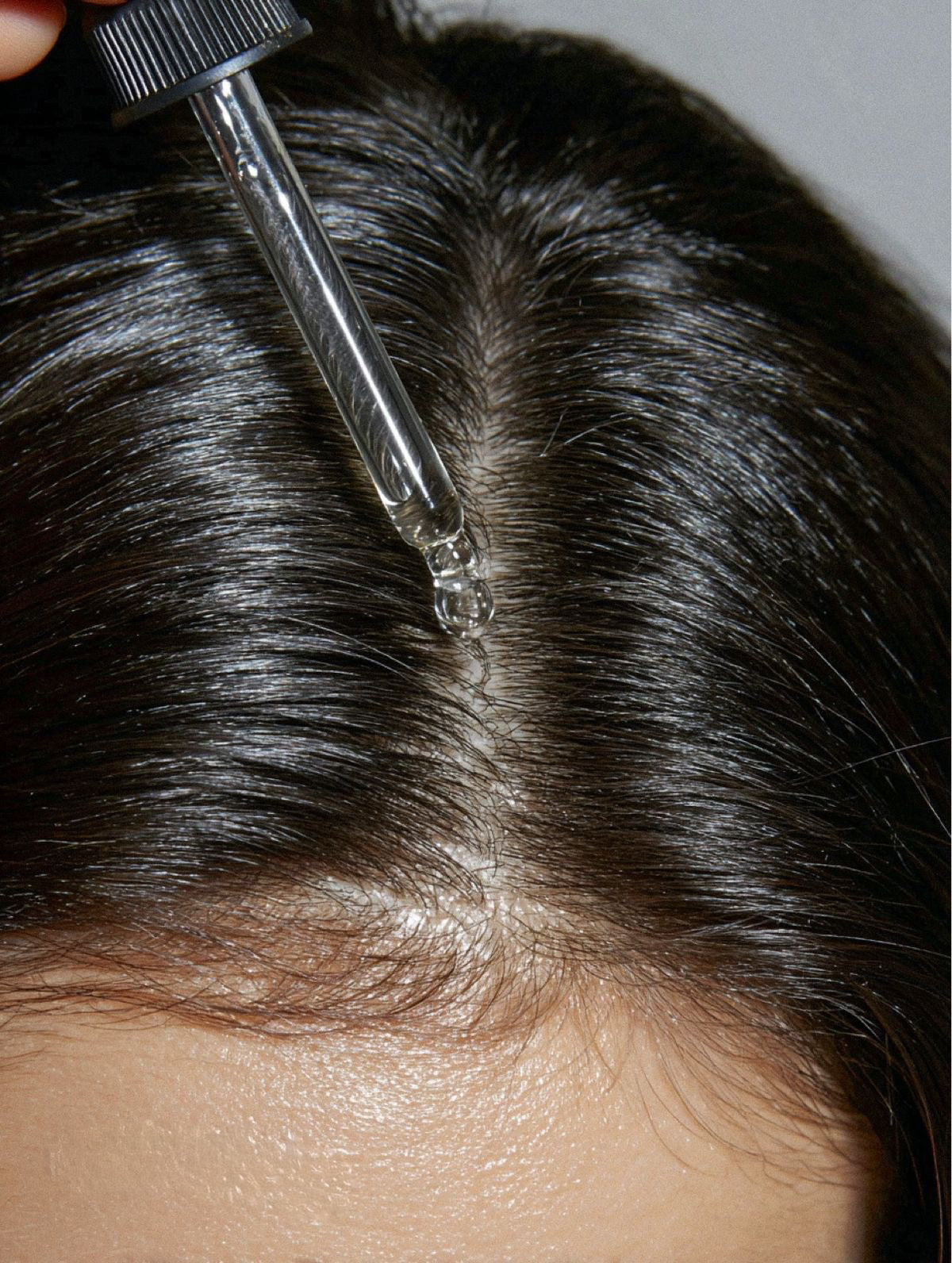 Aplicação de RituOil no couro cabeludo para hidratação, nutrição e fortalecimento dos fios