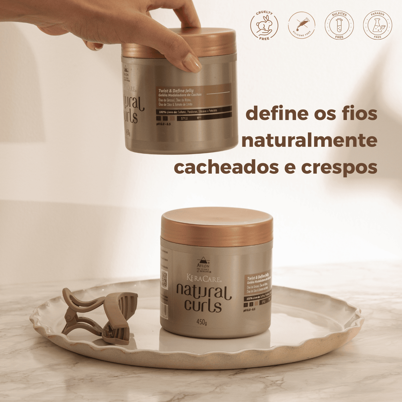 Foto da geléia ativadora de cachos em embalagem moderna, ao lado de ingredientes naturais como óleo de coco, girassol, rícino e limão. Produto para definição de cachos com brilho, fixação e sem resíduos.