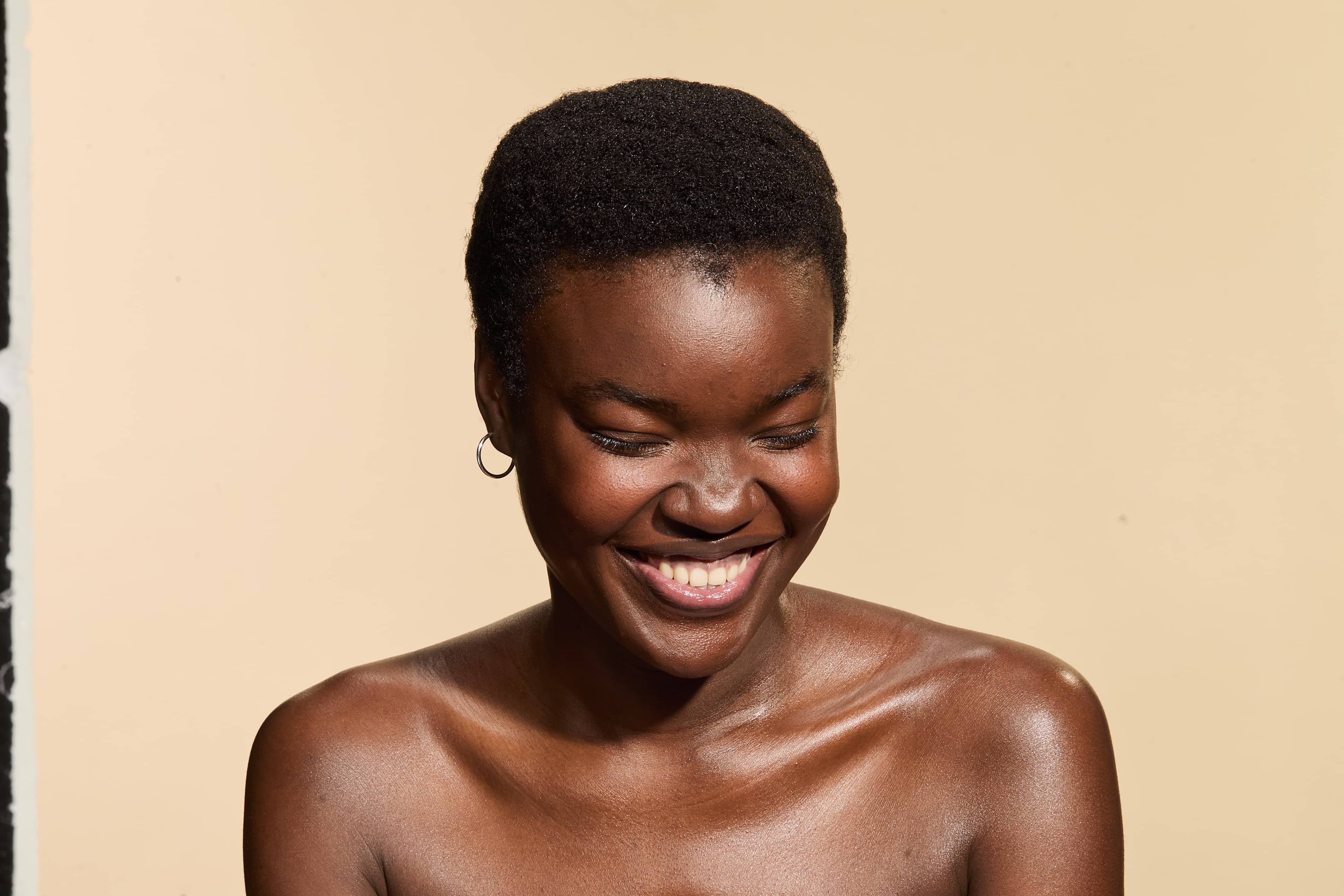 Modelo com cabelo 4C sorrindo enquanto usa produtos capilares Avlon, destacando cachos saudáveis, definidos, com brilho e hidratação.