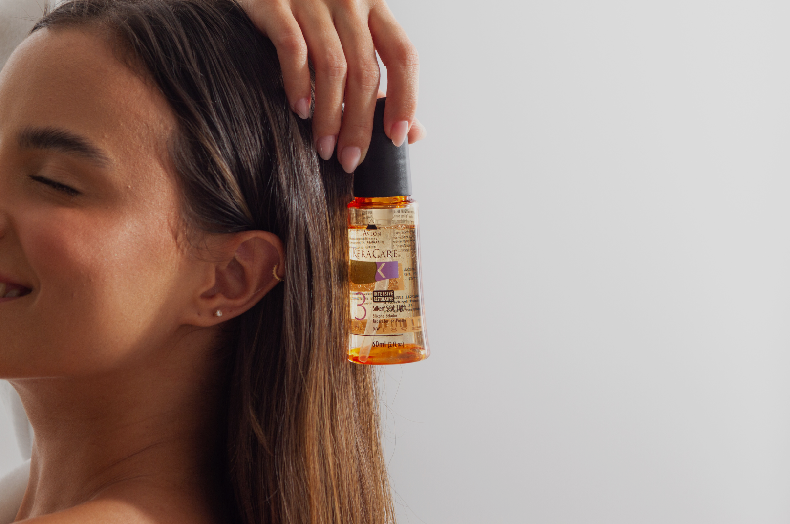 Modelo segurando o óleo capilar Silken Seal Light Oil, exibindo o produto em destaque