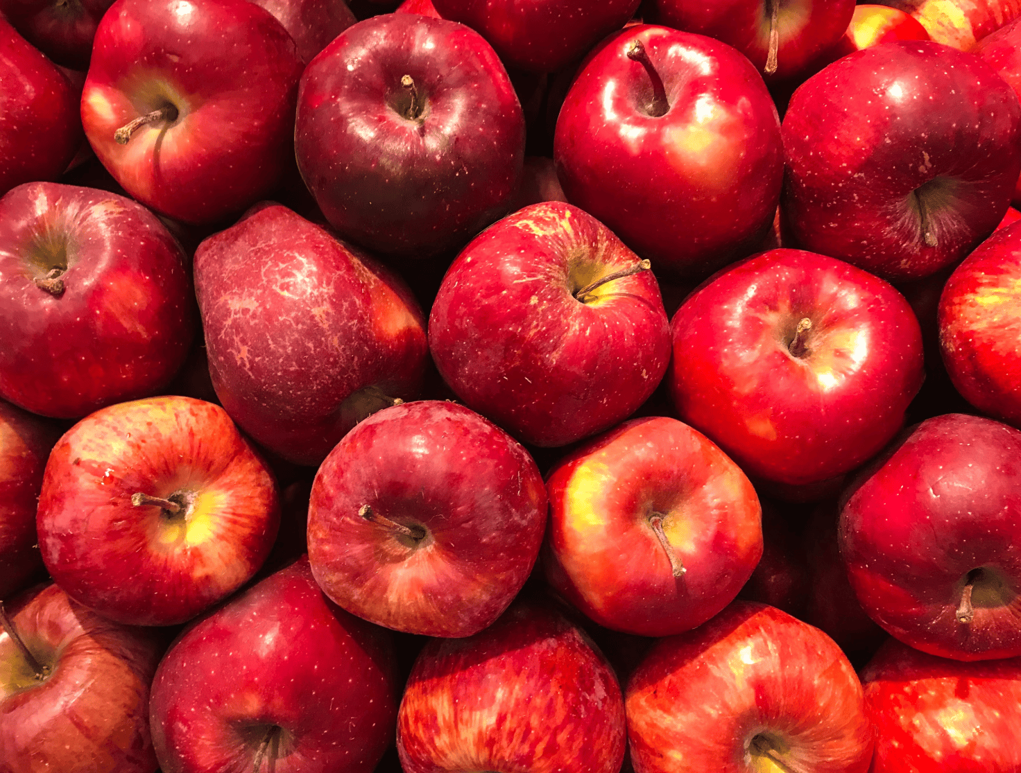 Maçãs frescas cortadas ao meio, destacando seus nutrientes naturais como vitaminas e antioxidantes que fortalecem o cabelo, estimulam o crescimento e promovem brilho saudável.